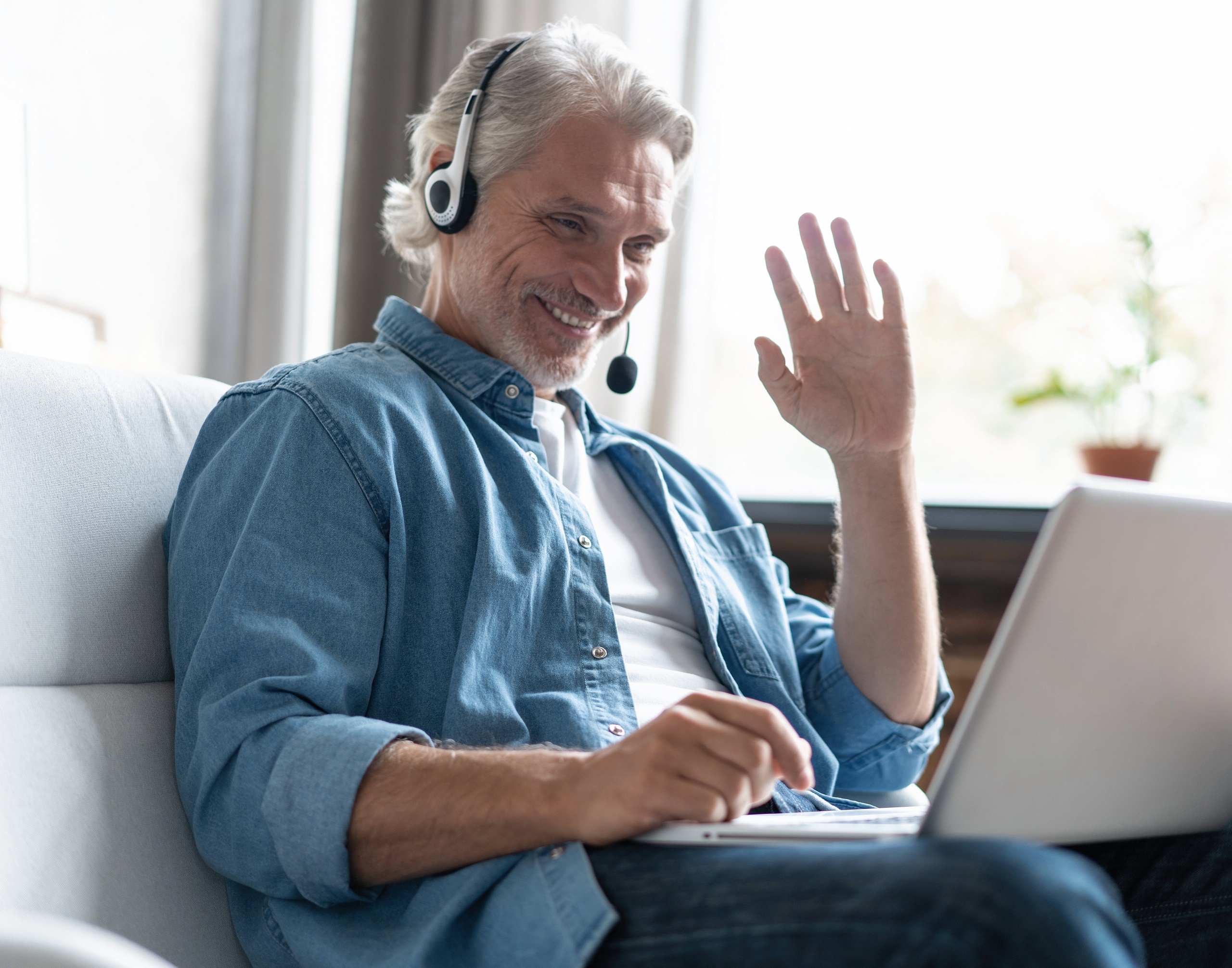 Smiling man in headset watch webinar or training on modern computer, male call center agent or telemarketer work consult client online